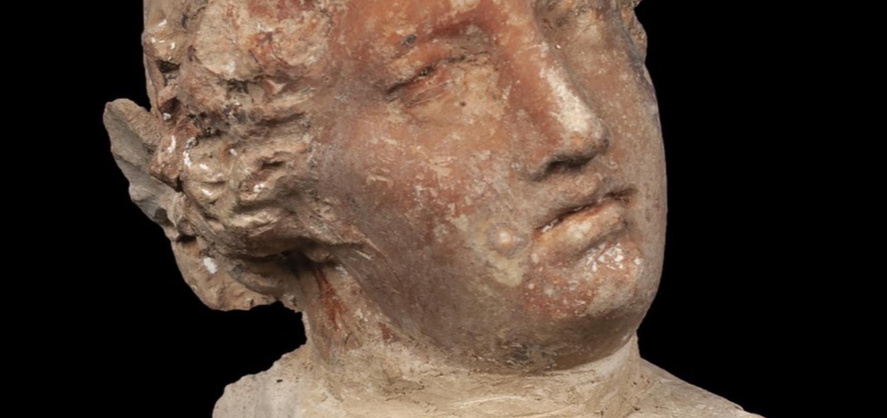 Very small statue of a head with Grecian-style hair.