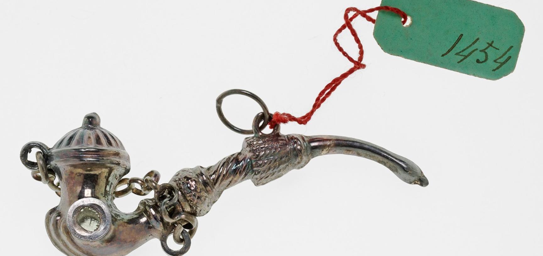 Tiny and intricate silver amulet representing a smoking pipe.