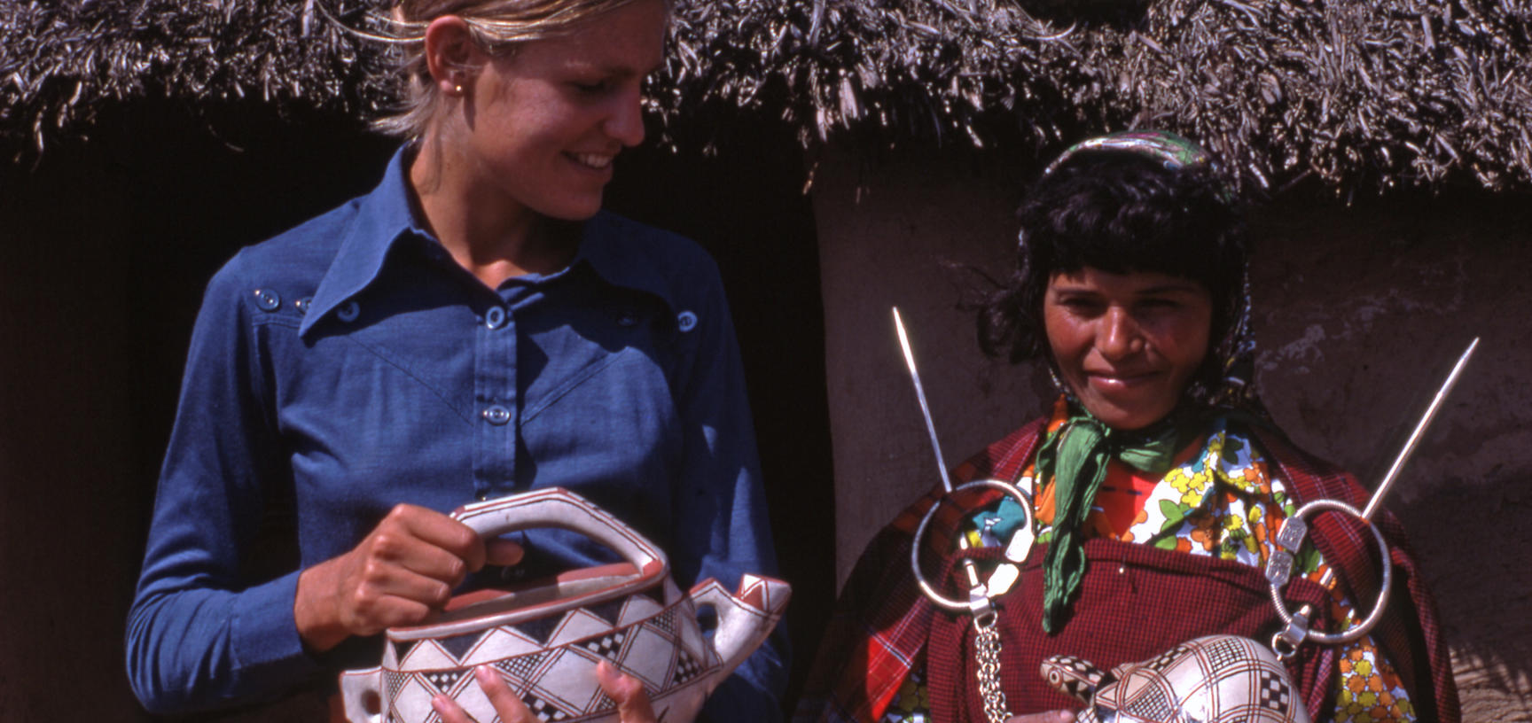 Two women holding pottery items  