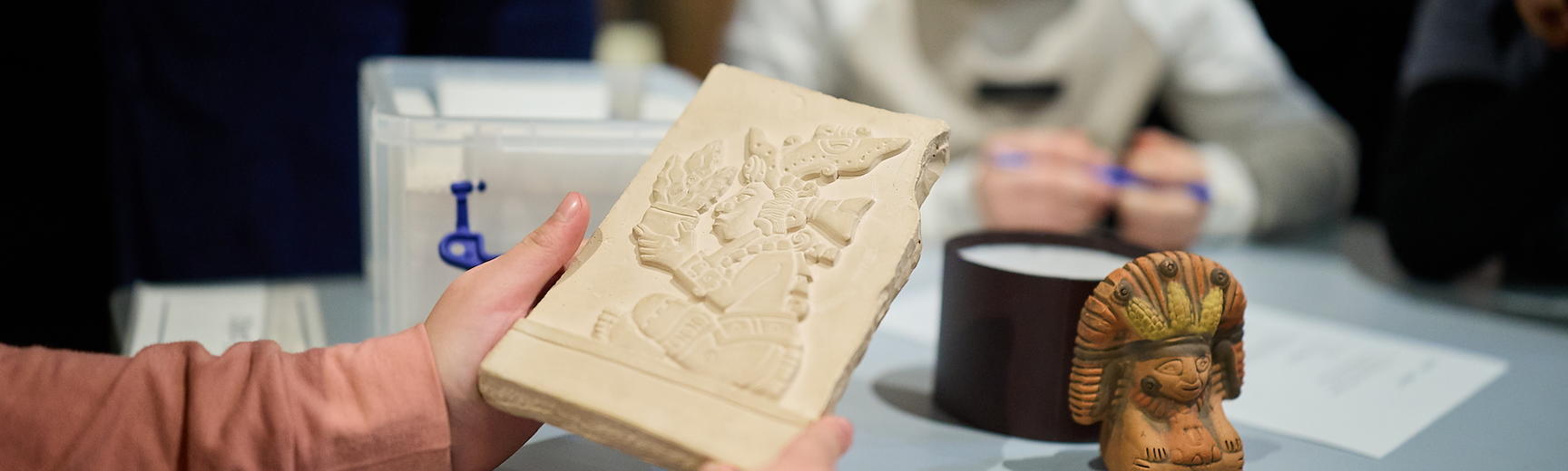 Close up of hands holding a plaster plaque with a smiling child in background.