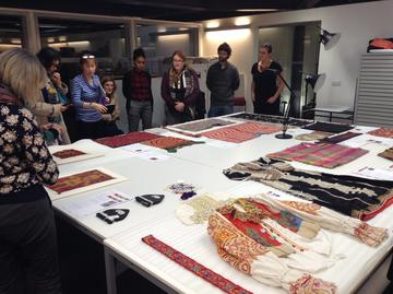 A group of people looking at textiles laid out on a table