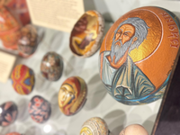View of a display case showing eggs elaborately painted with faces of people and geometric patterns.