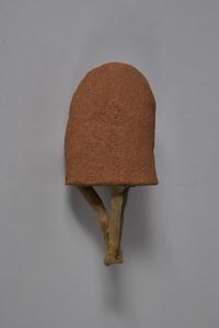 Wax figurine of a head, completely covered in a layer of laterite clay, with three wax cylinders attached to the bottom, joined together into a point