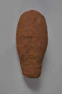 A lump of red laterite clay containing (not visible) a wax figurine and wire wrapping