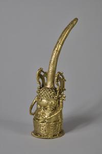 A polished bronze figure of a head with ornamentation and a bronze tusk emerging from the top