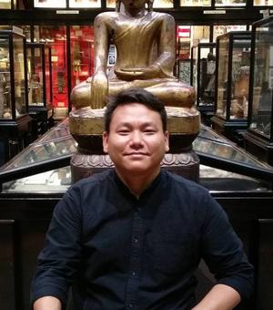 Thupten Kelsang in the Pitt Rivers Museum mimicking the pose of a buddha statue